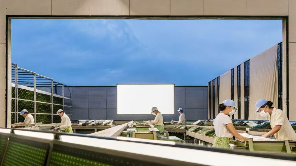 Workers processing materials in an open-air factory under blue sky