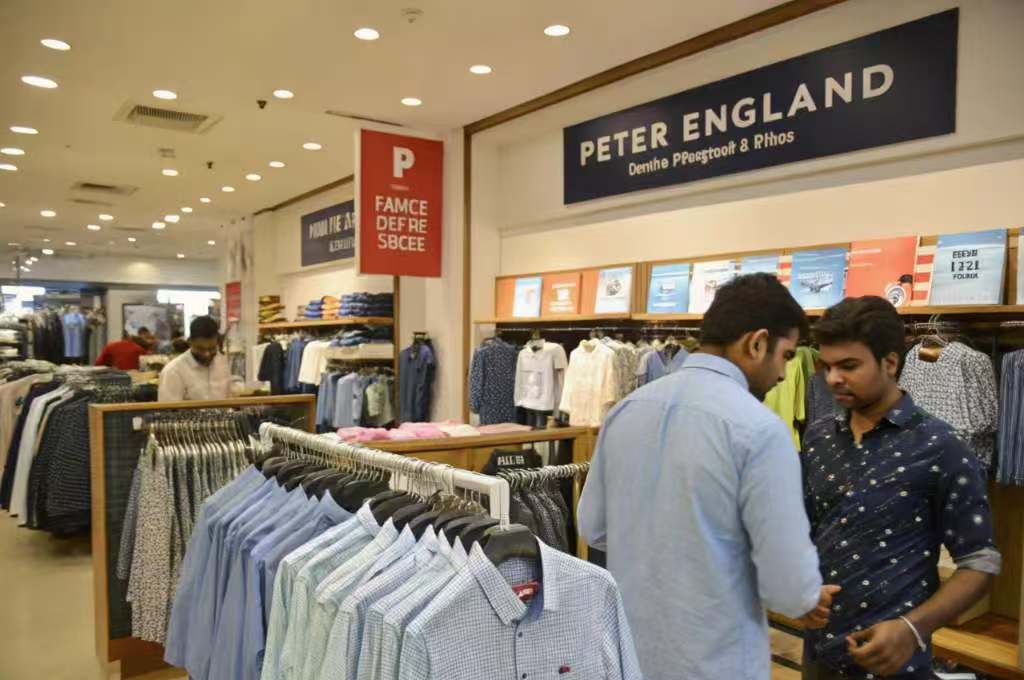 Shoppers browsing shirts in Peter England retail clothing store.