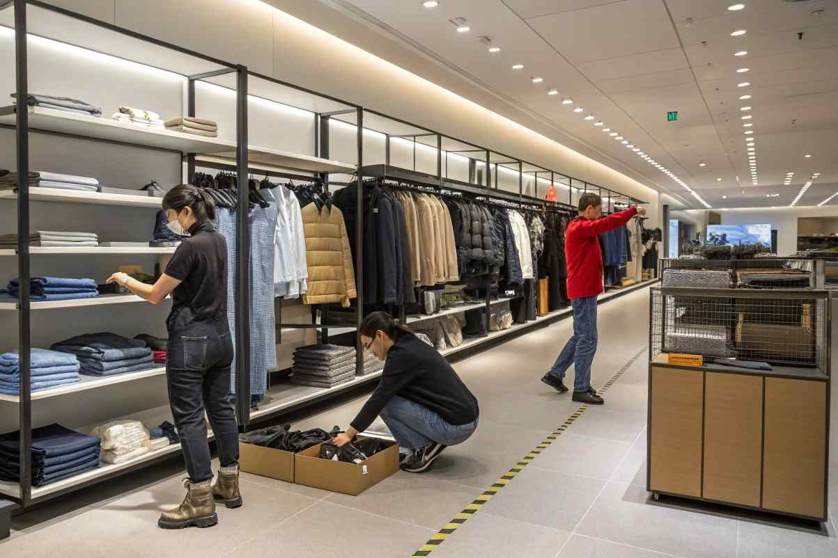 Employees organize and arrange clothes in a retail store, ensuring displays are neat and attractive.