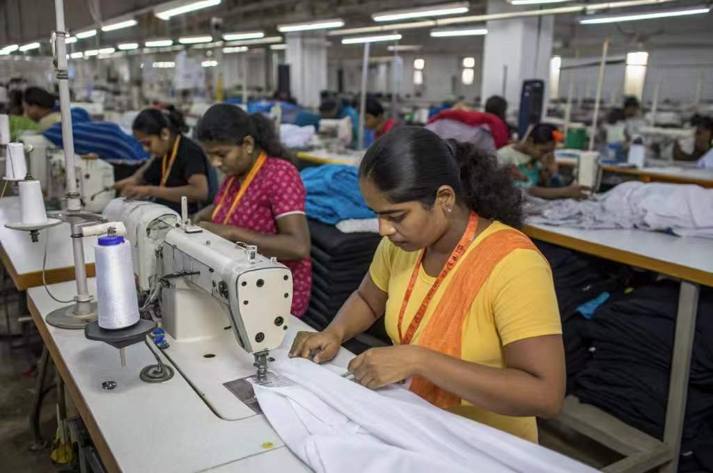 Women sewing garments on machines in a clothing factory.