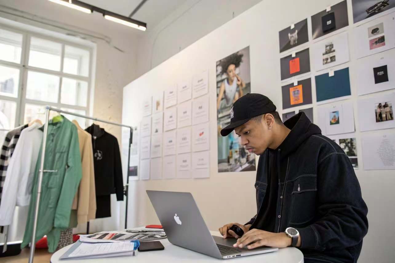 Young designer working on laptop in clothing design studio.