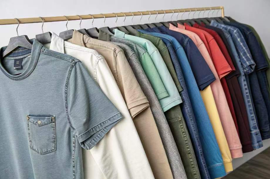 Colorful t-shirts neatly hanging on rack.
