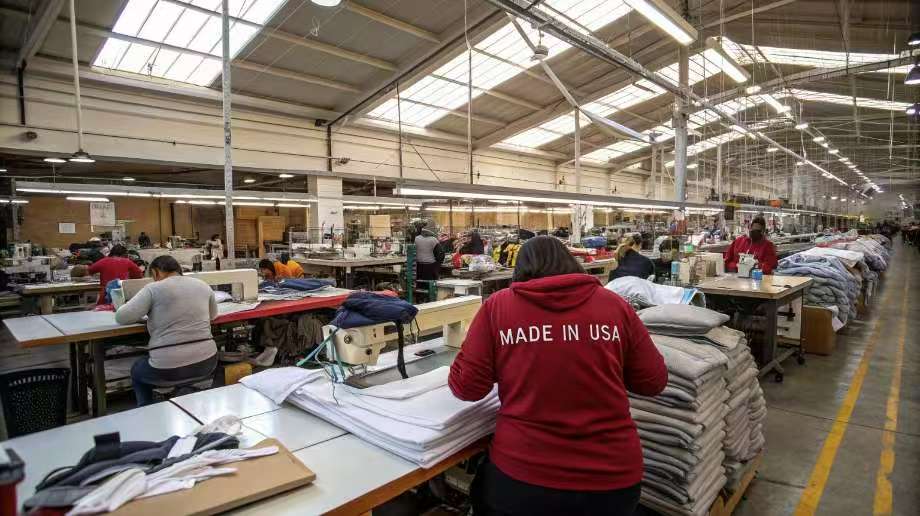 Workers sewing clothes in a large USA-made textile factory.