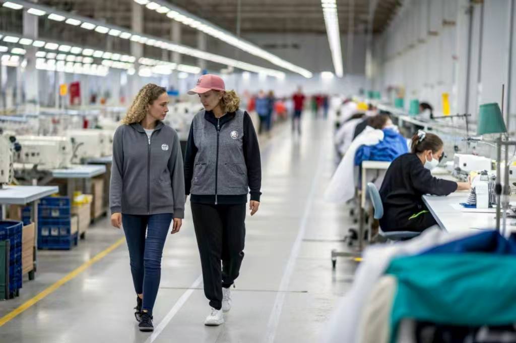 Two women walking through garment factory production floor