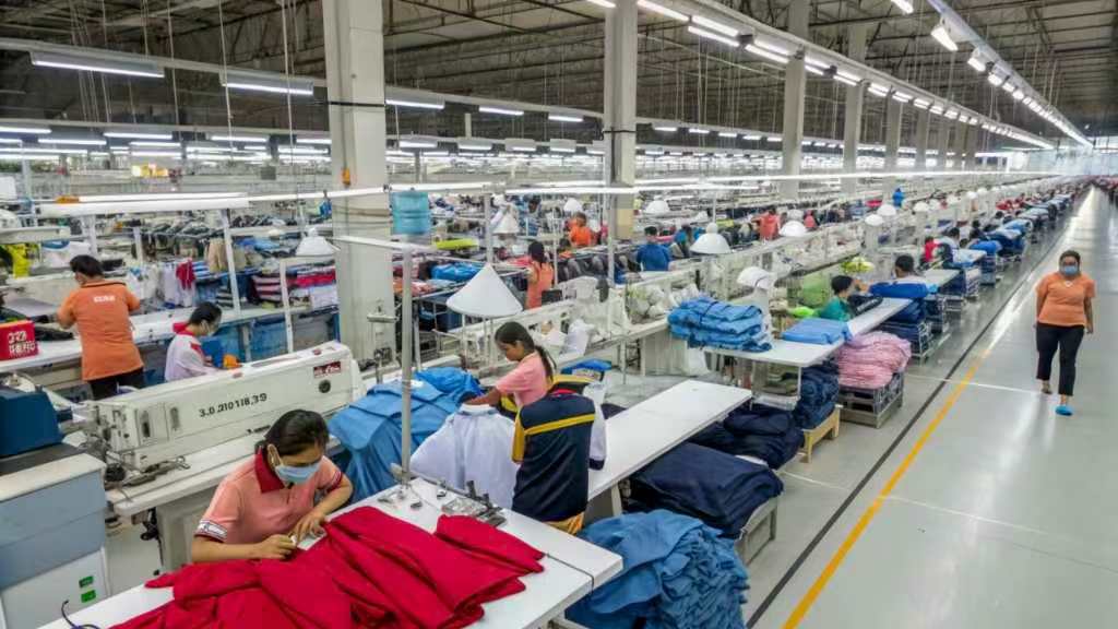 Large garment factory with rows of workers sewing and assembling clothes