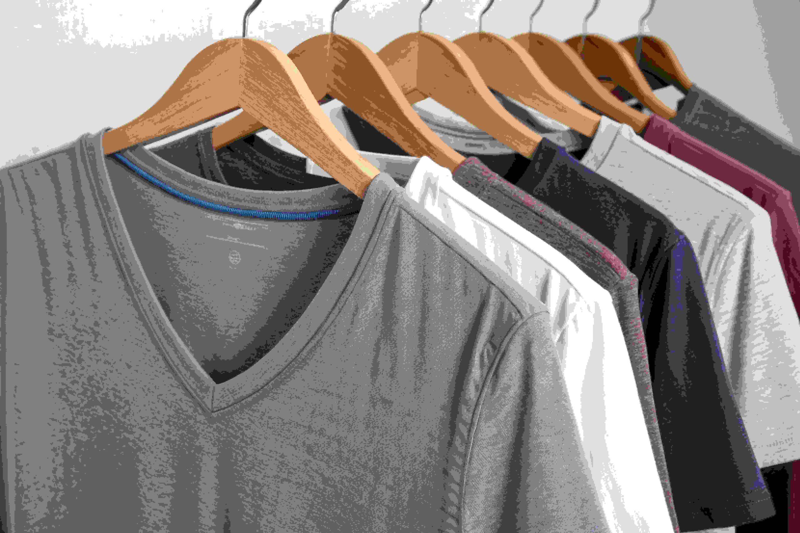 Colorful cotton t-shirts hanging on wooden hangers in a row